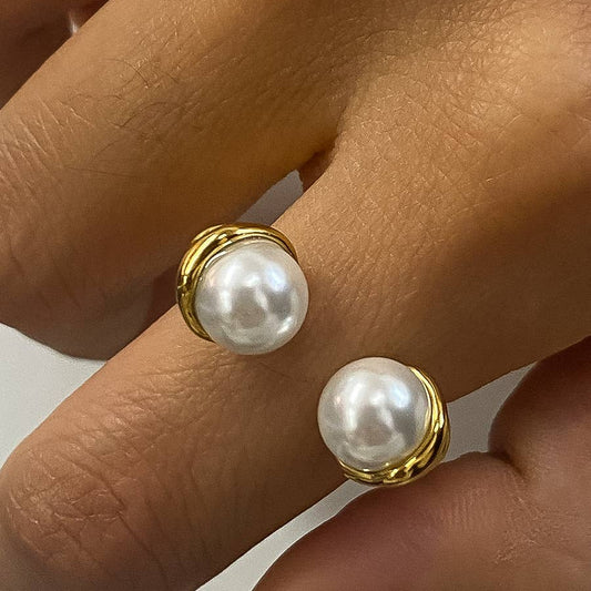 Yna Ring in 18K gold-plated stainless steel with pearls, held between fingers against a neutral background