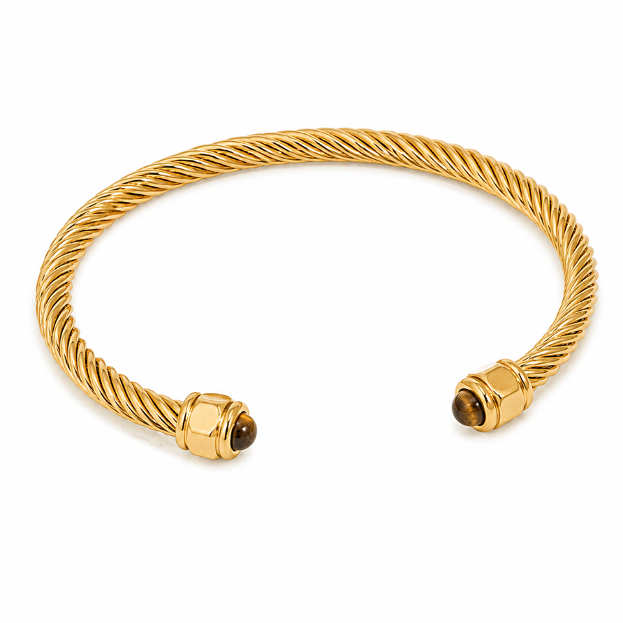 A gold cable-wrapped cuff bracelet with hexagonal gold end caps and small brown gemstone accents, shown on a clean white background.