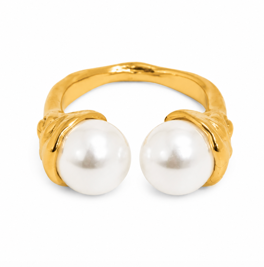 A gold ring featuring two large, round white pearls set in a sculptural, organic-shaped gold band, photographed on a clean white background.