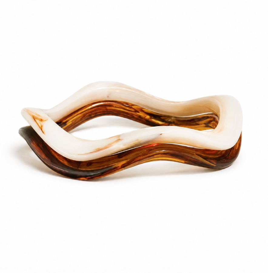 A wavy, open-ring resin tray or dish with a marbled pattern of translucent amber-brown and milky white, photographed on a seamless white background.